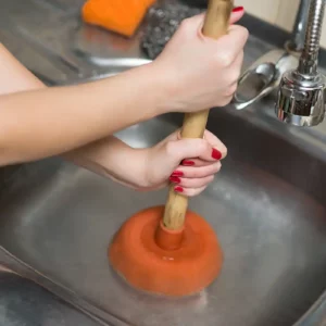 Toilet plunger being used to unclog sink