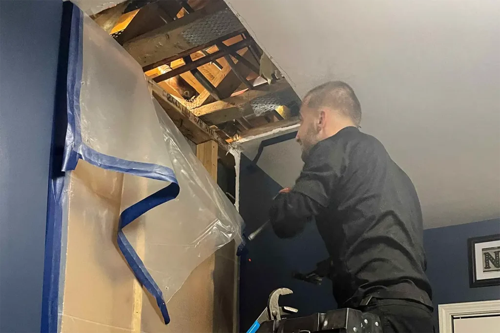 Licensed plumber removing drywall to locate water leak